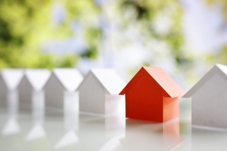 row of miniature houses with red one standing out in the middle