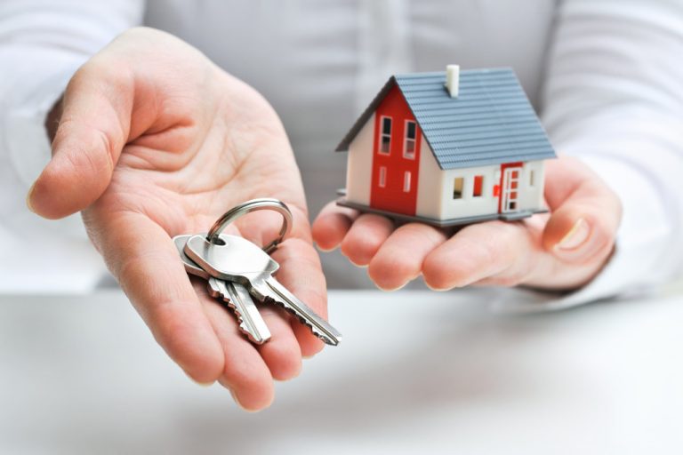 A real estate agent holding a miniature house and keys