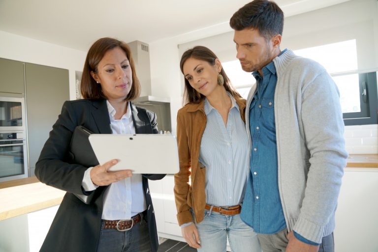 an agent showing a paper to house buyers